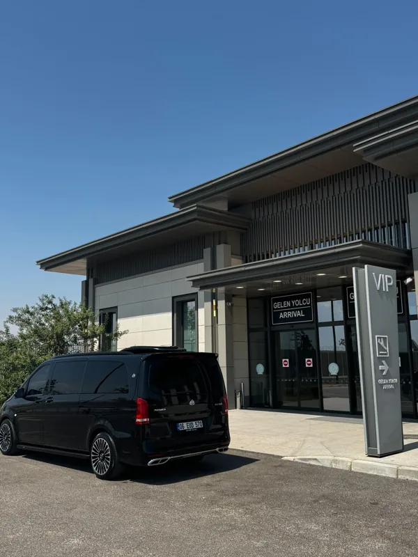 Havalimanının VIP terminali önünde gündüz park edilmiş siyah Mercedes minibüs.