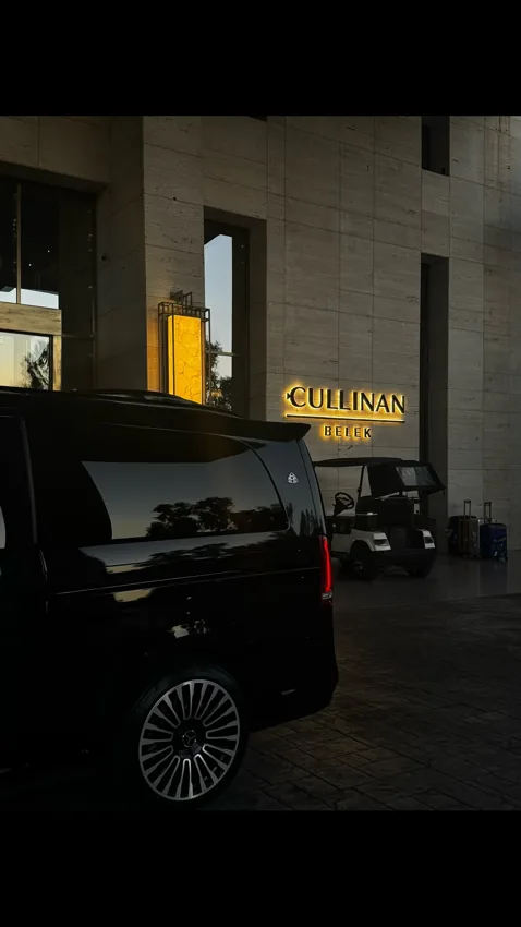 Cullinan Belek otelinin aydınlatılmış girişi önünde siyah minibüs.